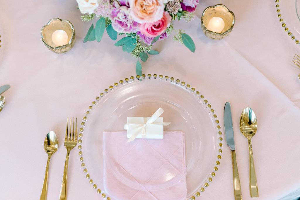 Close up of wedding reception table with gold flatware and blush linens
